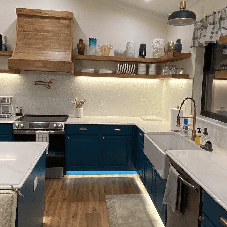 Modern kitchen with blue cabinetry, wooden shelves, and stylish appliances.