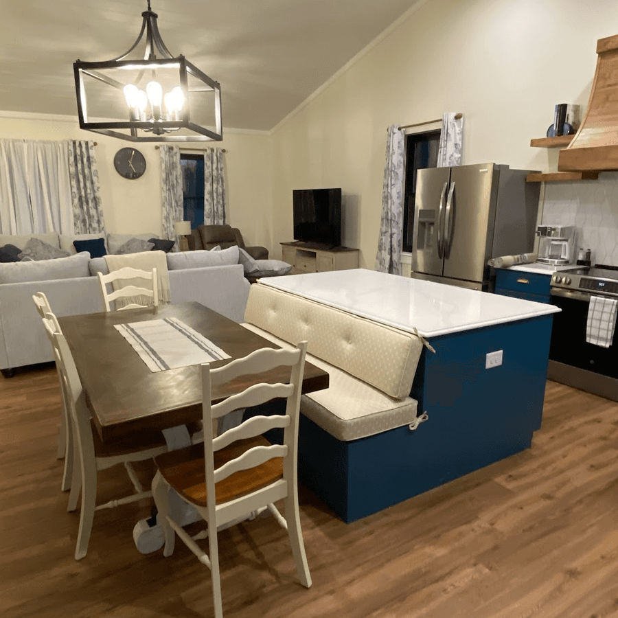 A modern kitchen and dining area featuring a wooden table, cushioned bench, and sleek appliances.